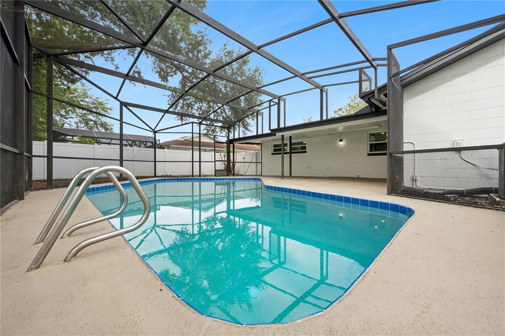 A swimming pool with a metal ladder is enclosed by a screened lanai — 1438 TIERRA CIRCLE, WINTER PARK, FL