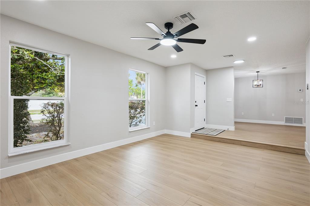 A bright living room features light wood-look flooring, two windows, and a black ceiling fan — 1438 TIERRA CIRCLE, WINTER PARK, FL