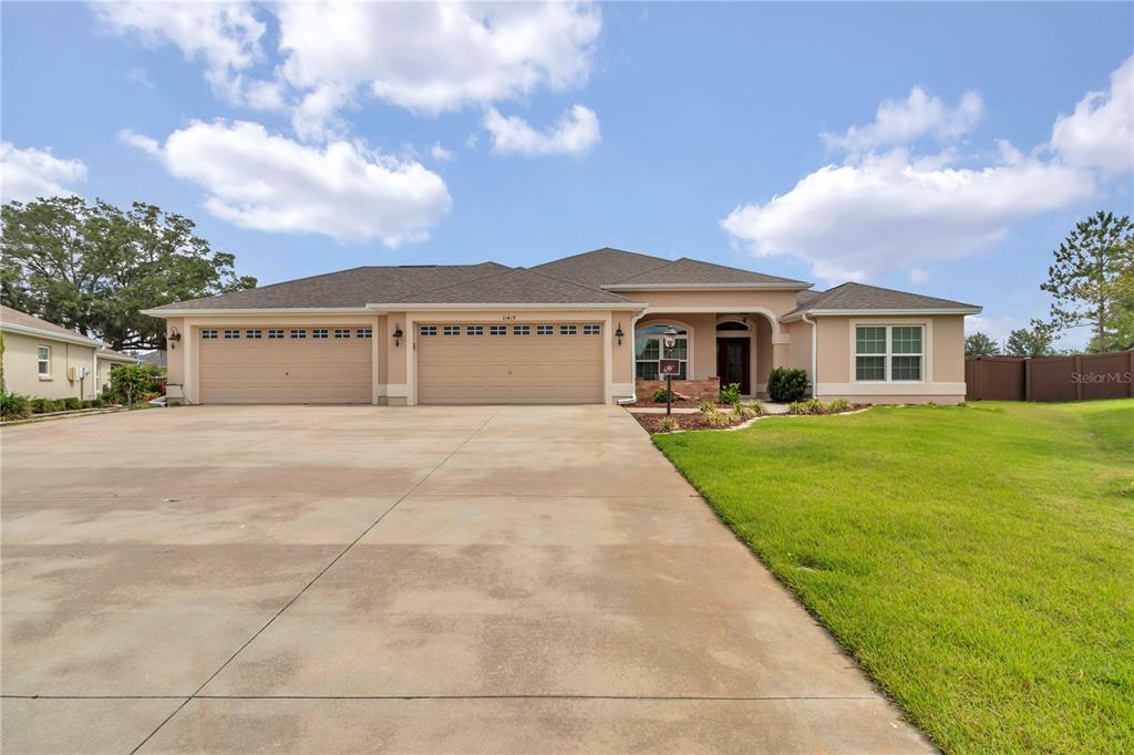 A single-story house with a large concrete driveway, three-car garage, and a manicured lawn — 11415 ZIMMERMAN PATH, OXFORD, FL