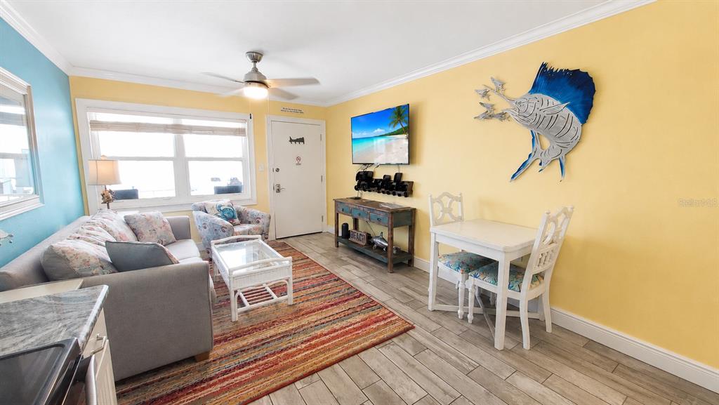 A living room features a sofa, dining set, television, and a large fish wall decoration — 8465 W GULF BOULEVARD UNIT 52, TREASURE ISLAND, FL