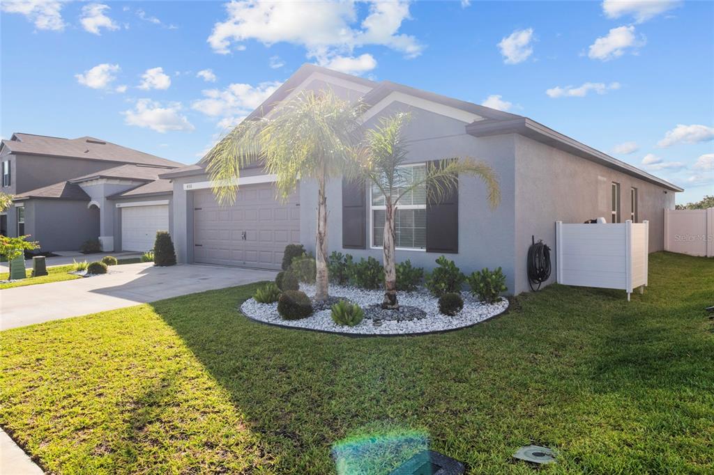 A single-story gray house with a two-car garage, palm trees, and a white privacy fence — 4316 FABULOUS FINCH LANE, BARTOW, FL