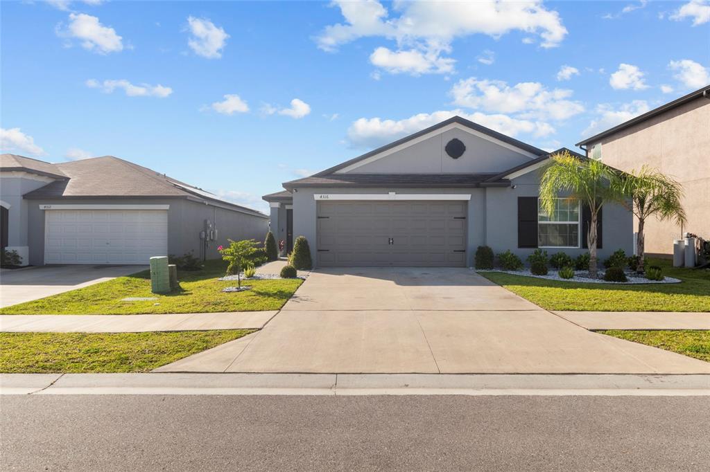 A single-story suburban house features a gray exterior, a two-car garage, and a palm tree — 4316 FABULOUS FINCH LANE, BARTOW, FL