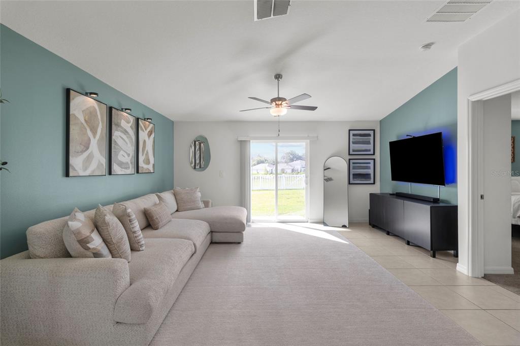 A living room features a large sectional sofa, a television on a console, and blue walls — 4316 FABULOUS FINCH LANE, BARTOW, FL