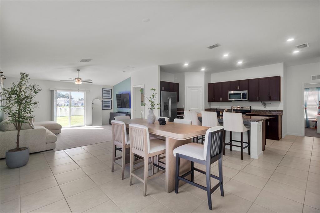 An open-concept kitchen and living area features tile flooring, dark cabinetry, and a dining island — 4316 FABULOUS FINCH LANE, BARTOW, FL