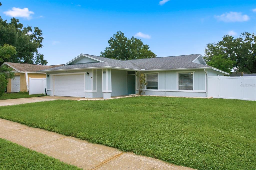 A light blue, single-story house with a white garage door and a front lawn — 14309 ARBOR HILLS ROAD, TAMPA, FL