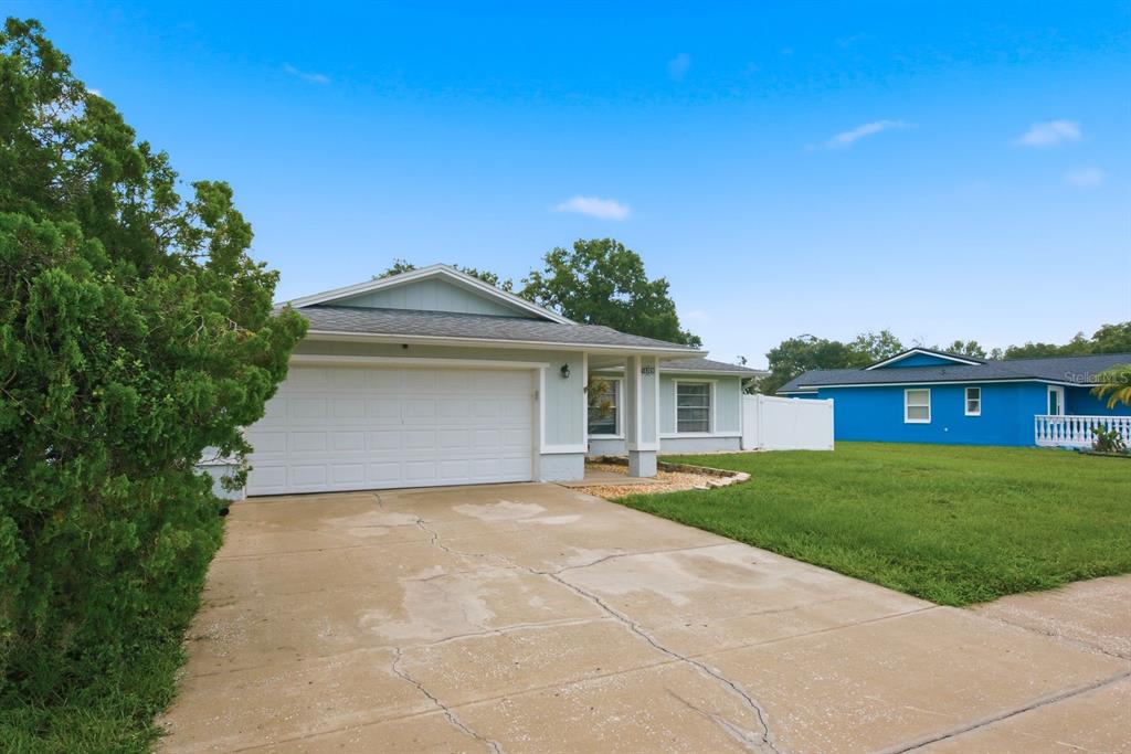A light-colored single-story house with a two-car garage and a concrete driveway — 14309 ARBOR HILLS ROAD, TAMPA, FL