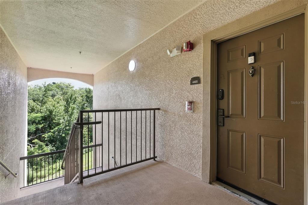 An exterior view of an apartment entrance with a brown door and metal railing — 8000 TUSCANY WAY UNIT 4405, DAVENPORT, FL