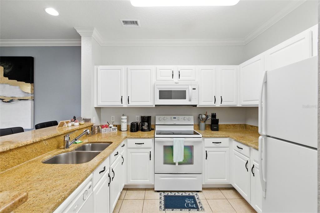 A kitchen features white cabinets, granite countertops, stainless steel appliances, and a double-basin sink — 8000 TUSCANY WAY UNIT 4405, DAVENPORT, FL