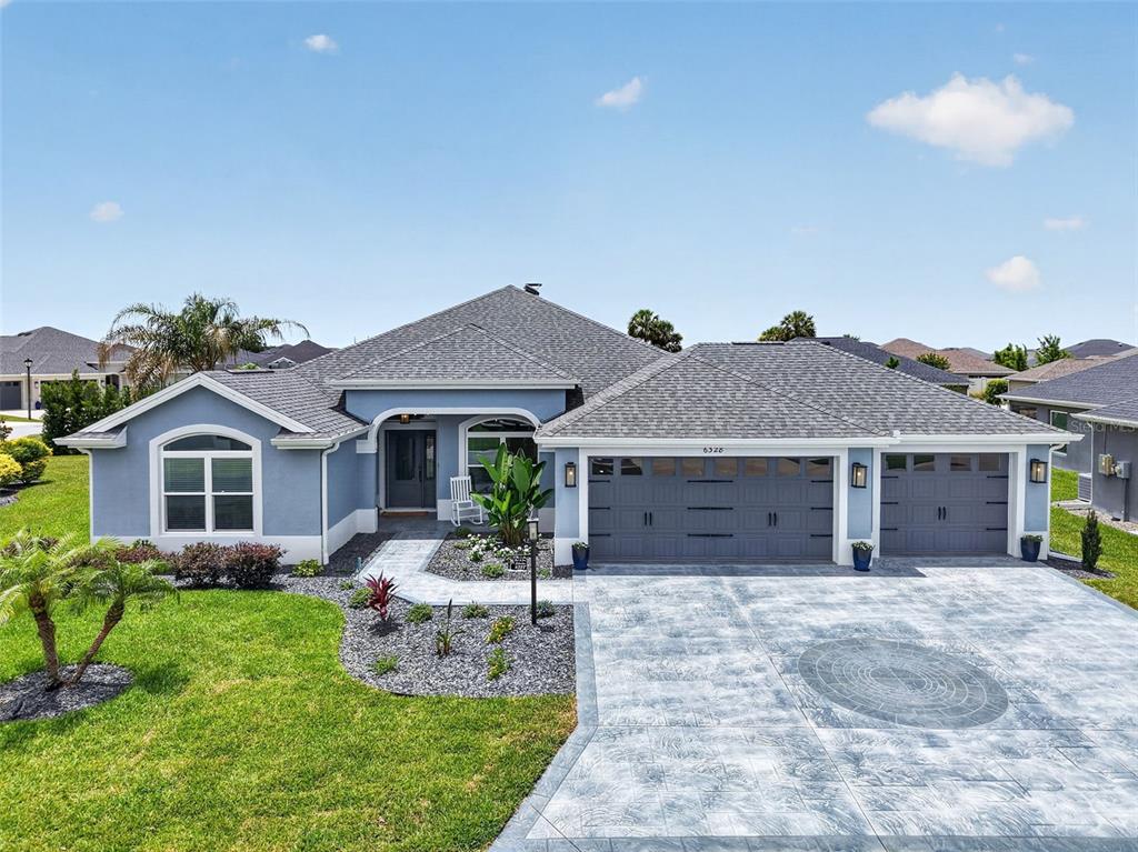 A single-story blue house with a gray roof and a stamped concrete driveway — 6328 MERHOTTEIN LOOP, THE VILLAGES, FL