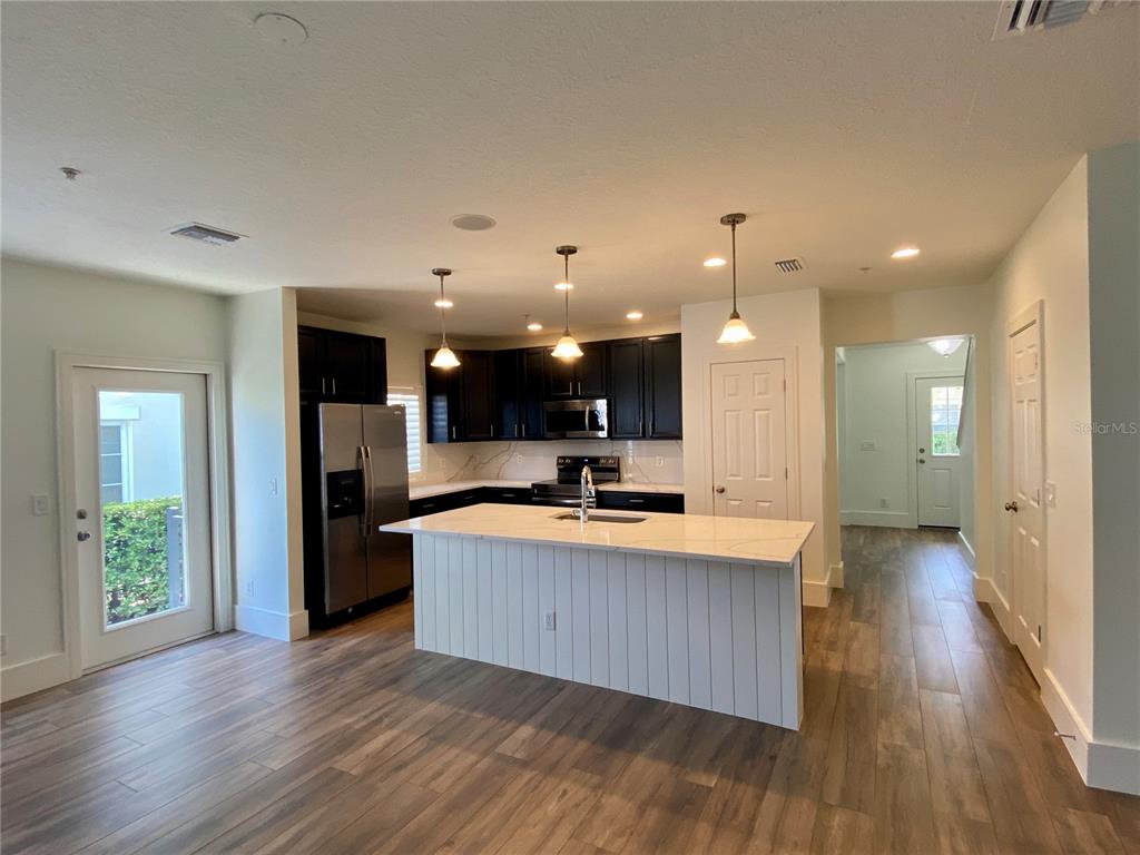 A kitchen features dark cabinets, a white quartz island, and wood-look flooring — 2856 KEMPER AVENUE, ORLANDO, FL