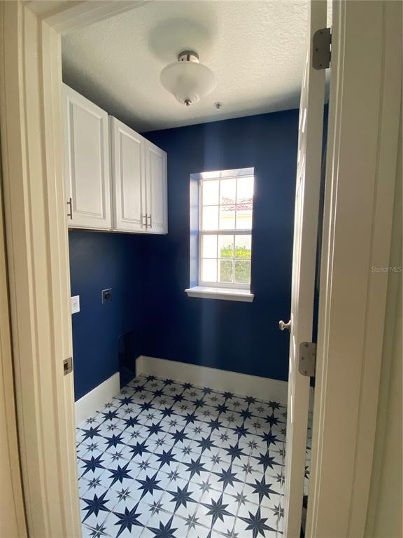A laundry room features dark blue walls, white upper cabinets, and patterned star-tiled flooring — 2856 KEMPER AVENUE, ORLANDO, FL