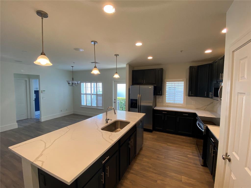A kitchen features a large island with a white countertop, dark cabinets, and stainless appliances — 2856 KEMPER AVENUE, ORLANDO, FL