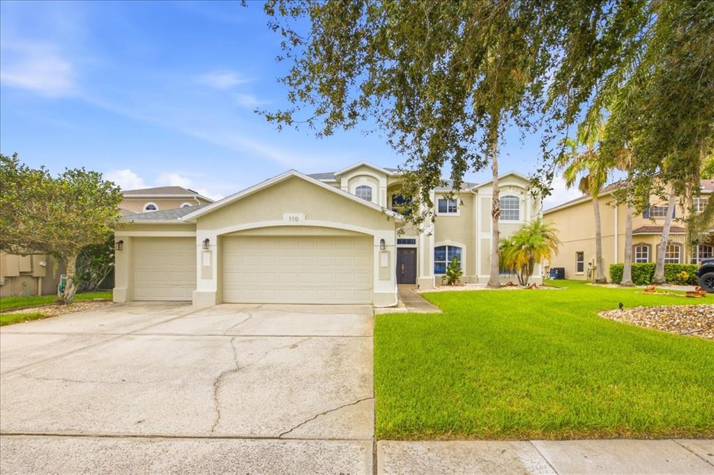 A two-story suburban house with a three-car garage and a large front lawn — 110 BURRELL CIRCLE, KISSIMMEE, FL