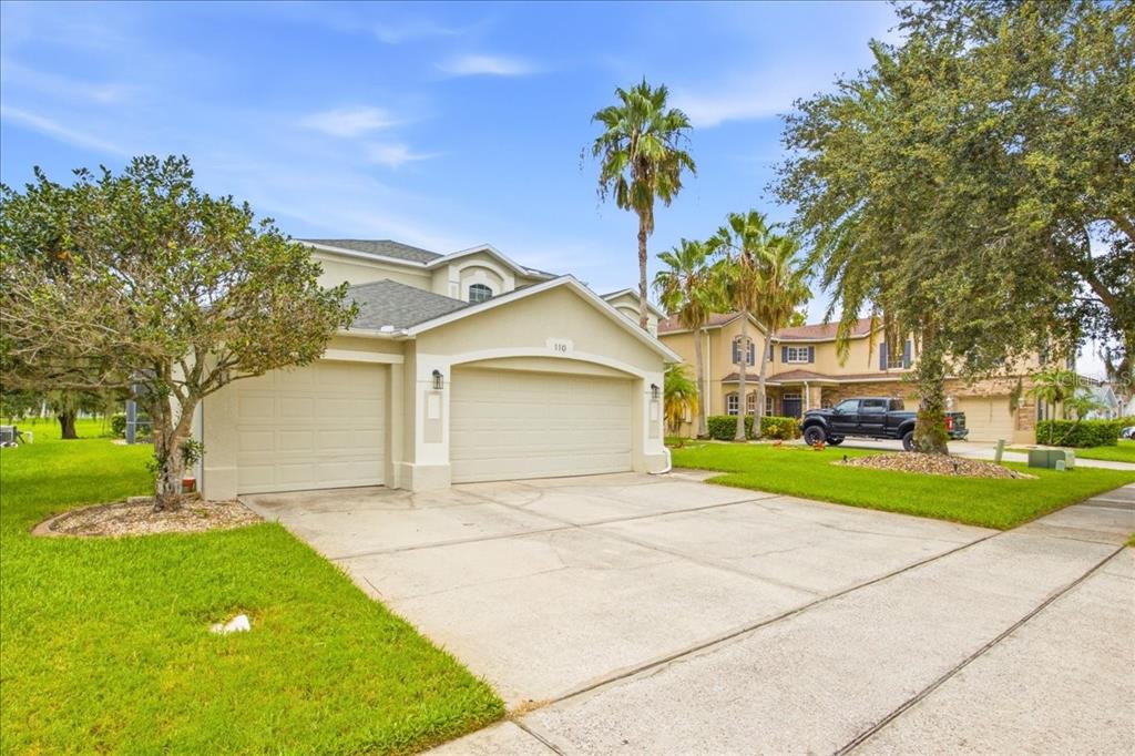 A beige two-story house features a three-car garage and a concrete driveway — 110 BURRELL CIRCLE, KISSIMMEE, FL