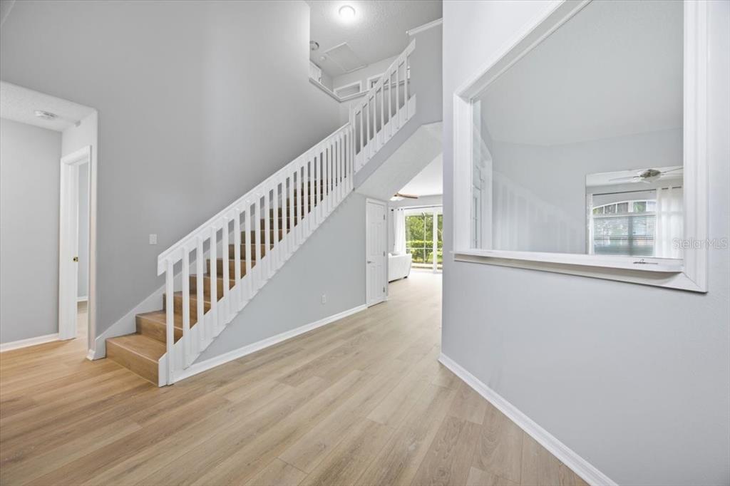 An entryway features light wood-look flooring, a white staircase, and a large interior window — 110 BURRELL CIRCLE, KISSIMMEE, FL