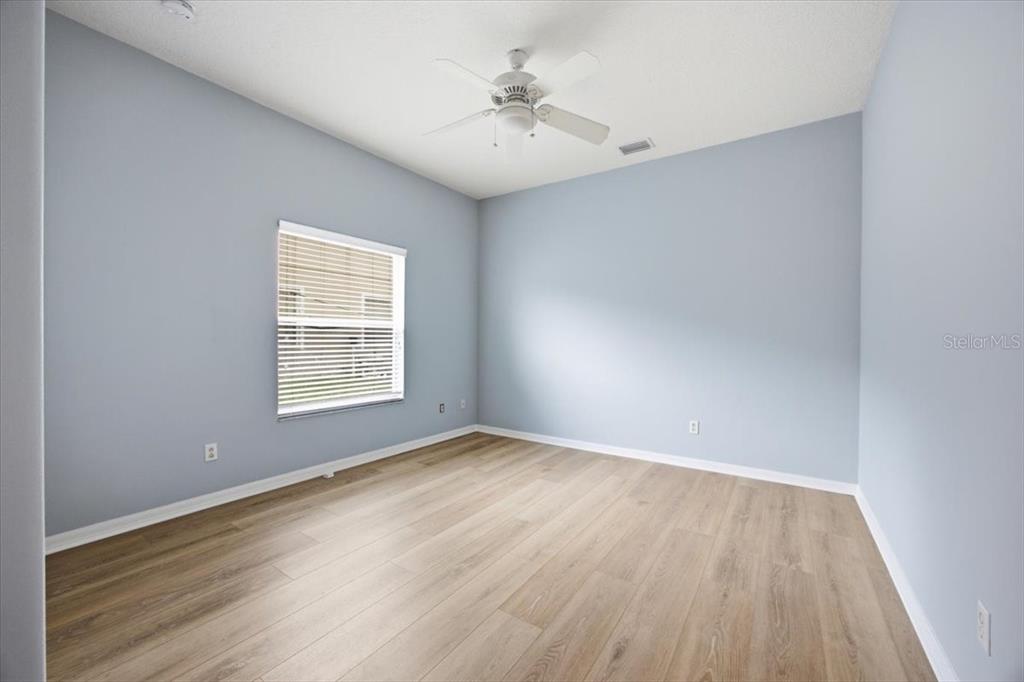 An empty bedroom features light blue walls, wood-look flooring, and a white ceiling fan — 110 BURRELL CIRCLE, KISSIMMEE, FL