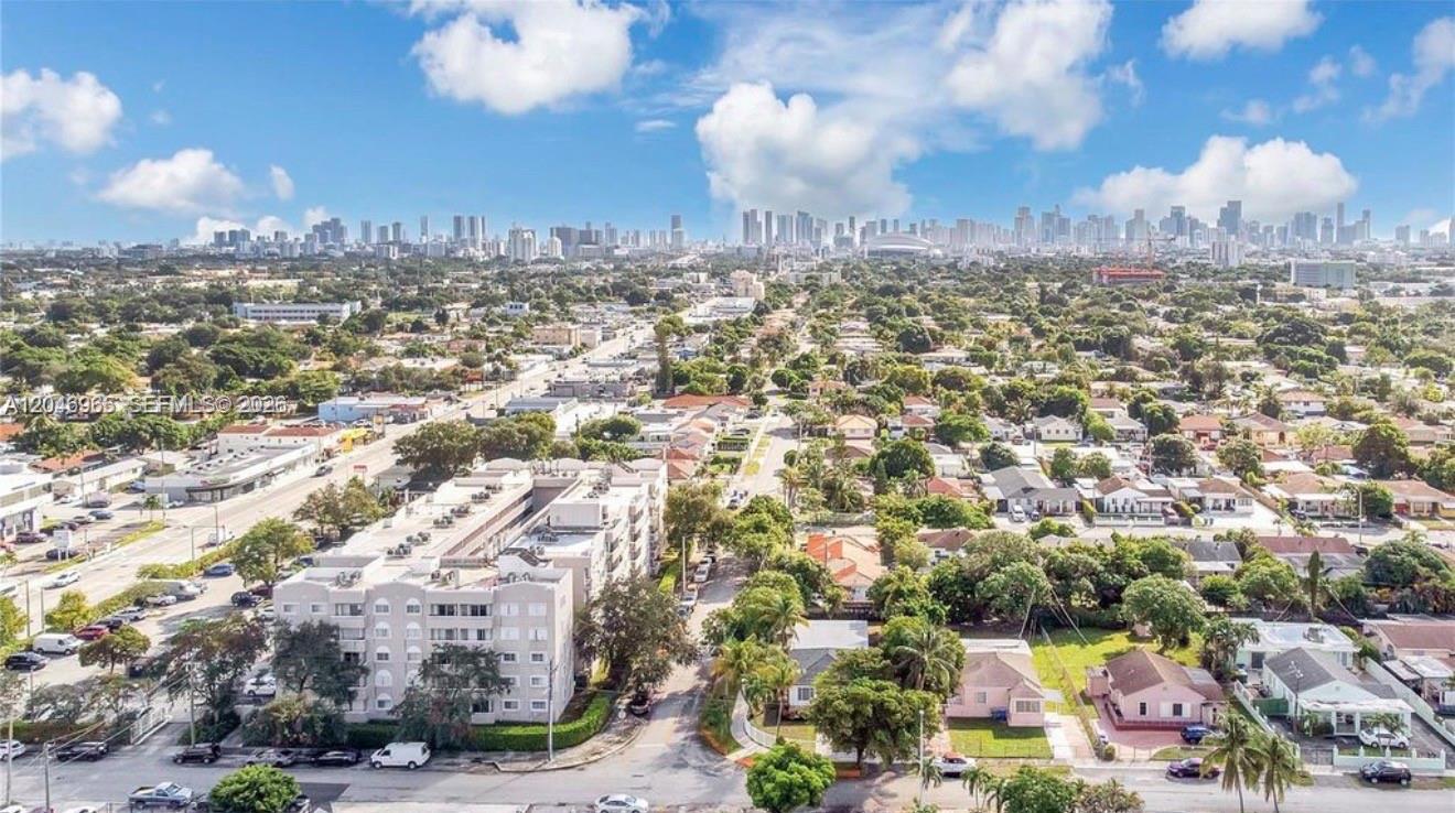 An aerial view shows a residential neighborhood with a large apartment building and city skyline — 521 NW 33rd Ave # 1, Miami FL 33125, MIAMI, FL