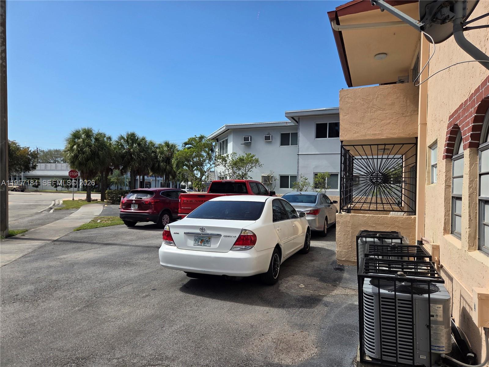 An outdoor parking area with several cars parked in front of a multi-story apartment building — 6373 SW 8th St, Miami FL 33144, MIAMI, FL