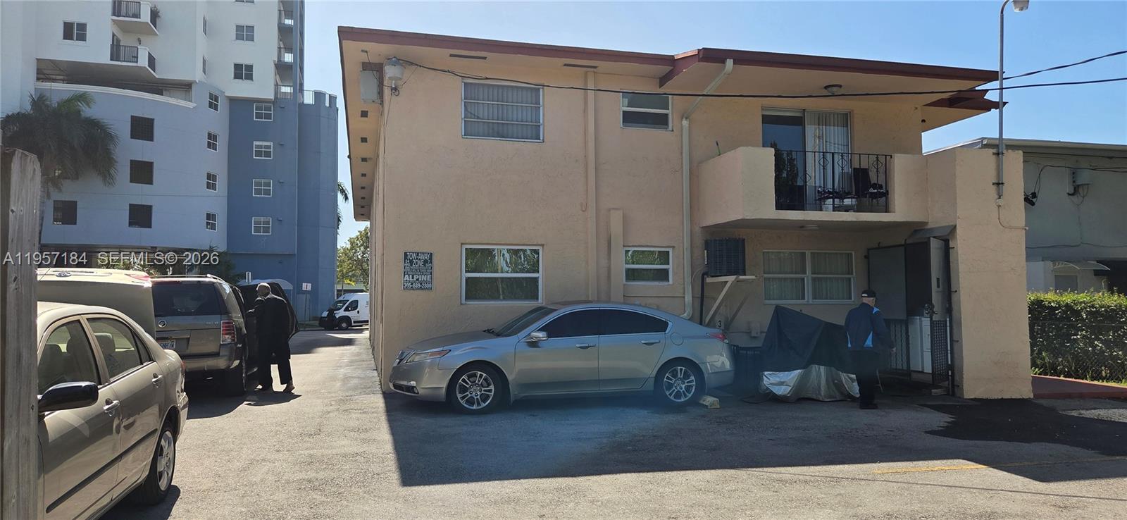 The exterior of a two-story tan building features a parking area with several parked cars — 6373 SW 8th St, Miami FL 33144, MIAMI, FL