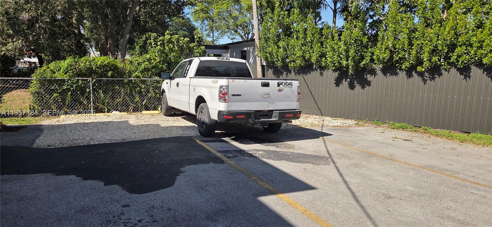A white Ford pickup truck is parked on a gravel lot next to a fence — 6373 SW 8th St, Miami FL 33144, MIAMI, FL