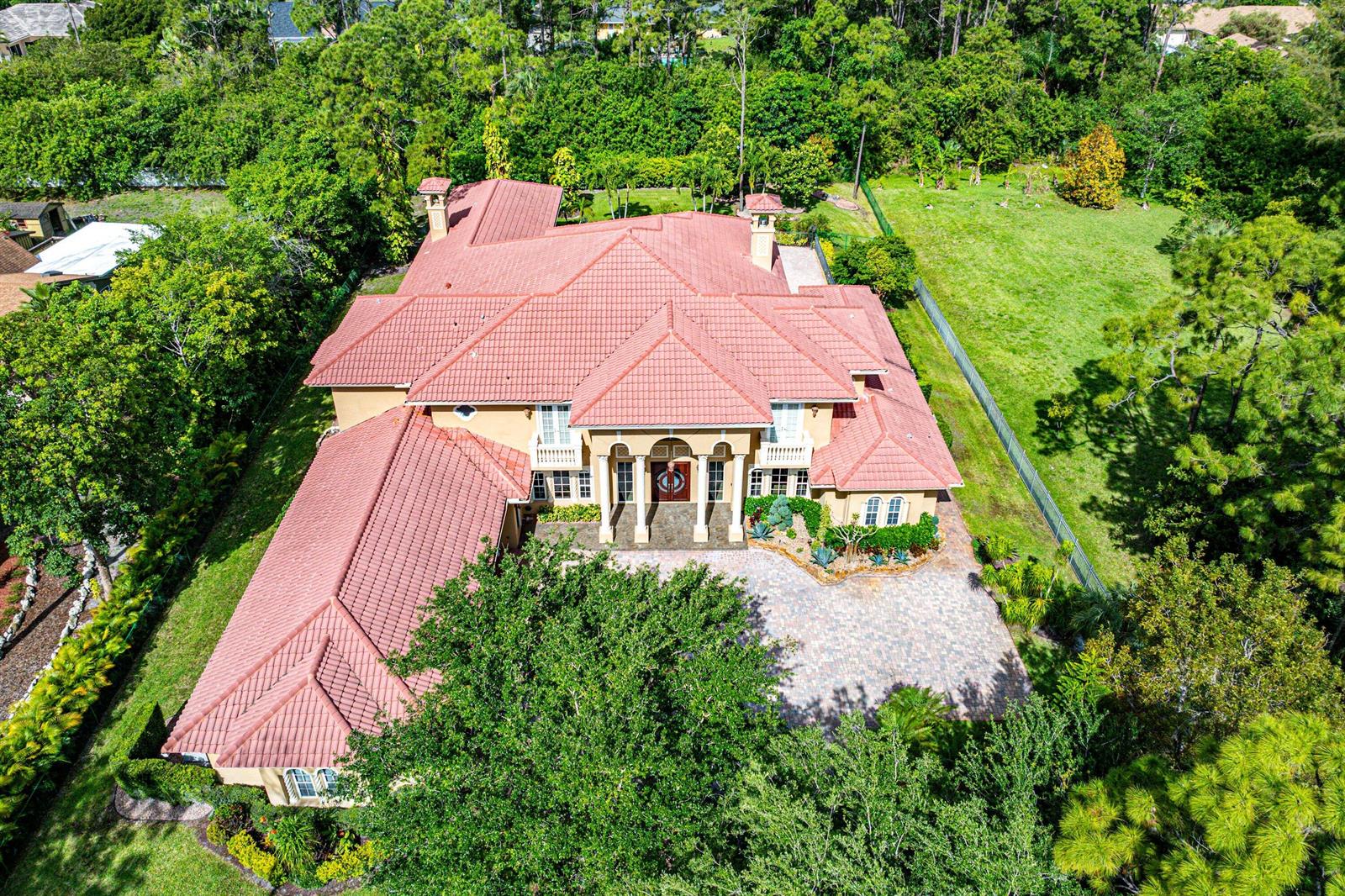 An aerial view of a large, two-story house with a red tile roof and driveway — 6071 NW 69th Way, Parkland FL 33067, PARKLAND, FL