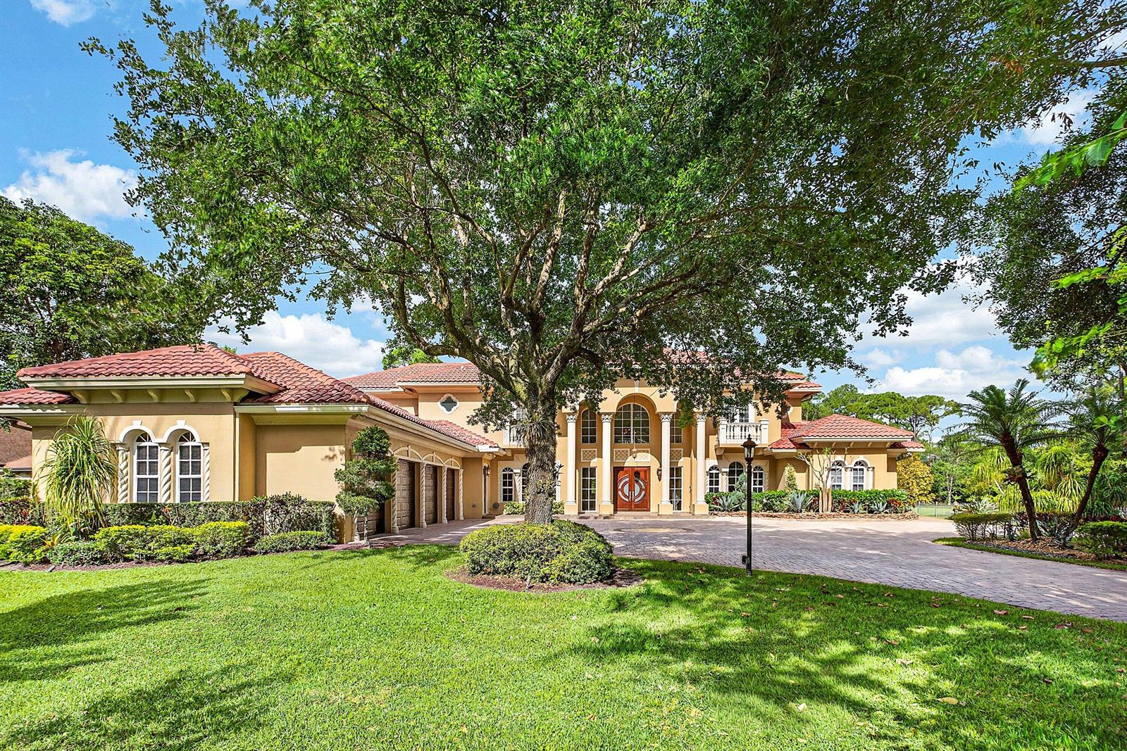 A large two-story Mediterranean-style house features a tiled roof, arched windows, and a paved driveway — 6071 NW 69th Way, Parkland FL 33067, PARKLAND, FL