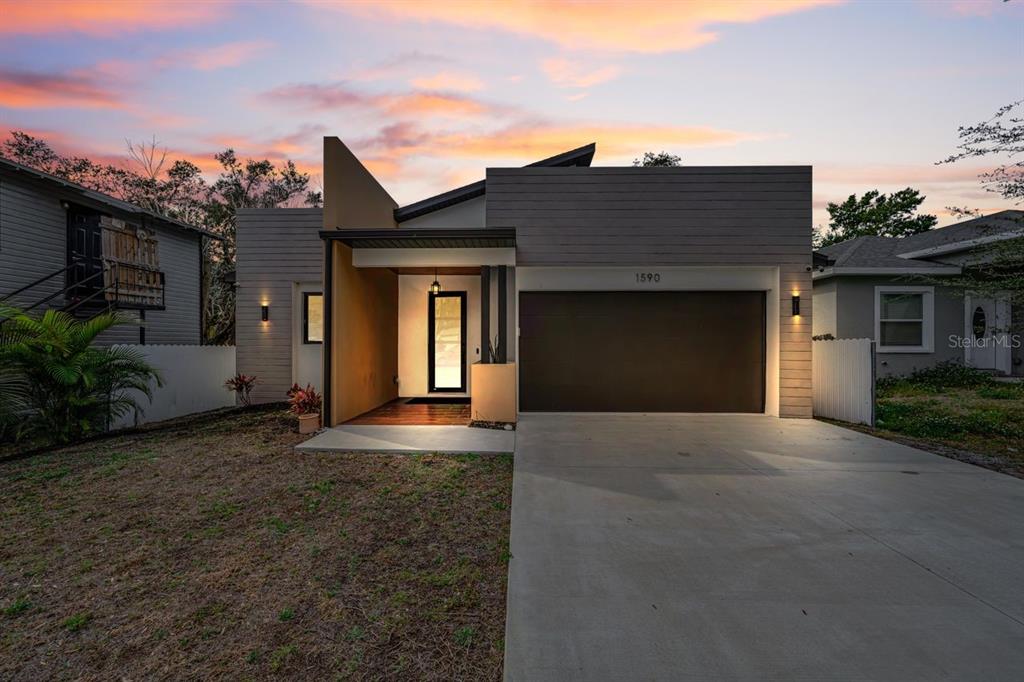 A modern single-story house with a flat roof, a garage, and a wooden front porch — 1590 S WASHINGTON AVENUE, CLEARWATER, FL