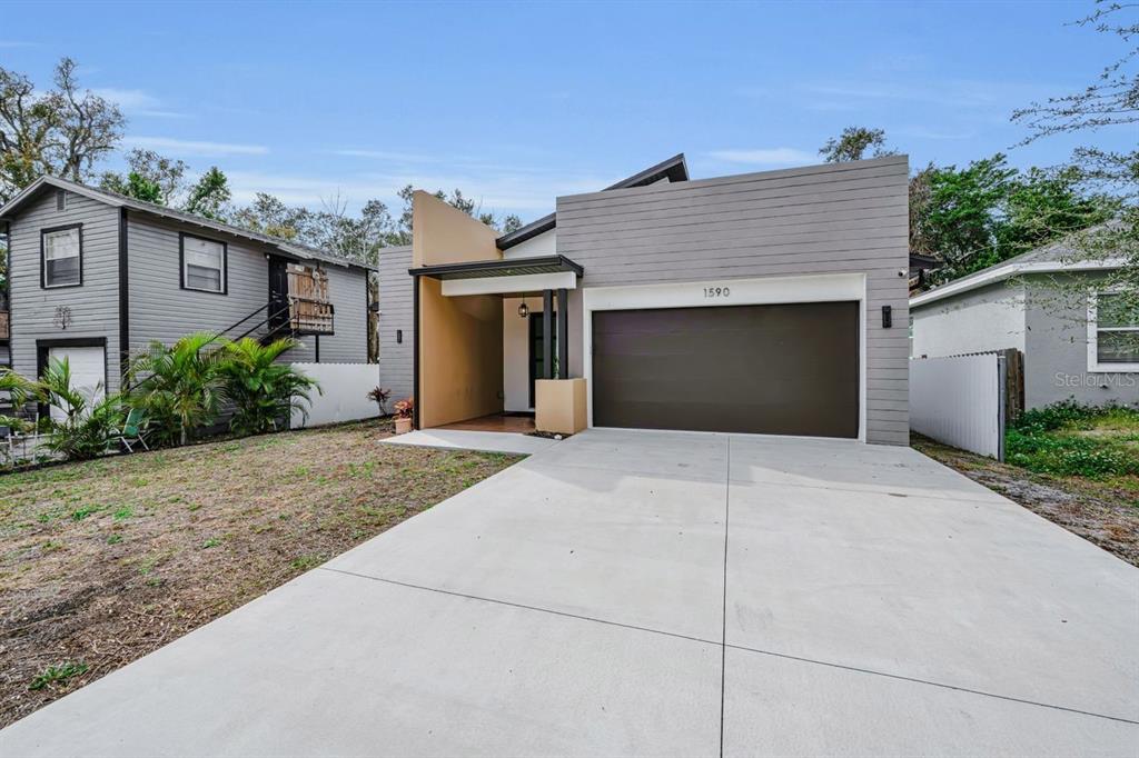 A modern single-story house with a concrete driveway, a two-car garage, and a tan entryway — 1590 S WASHINGTON AVENUE, CLEARWATER, FL