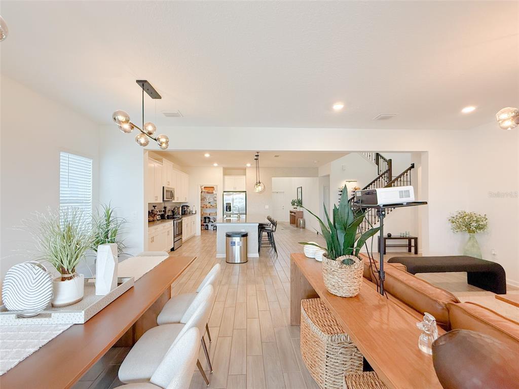 An open-concept living and dining area features light wood-look tile floors and a modern kitchen — 13993 TITLE WAY, WINTER GARDEN, FL