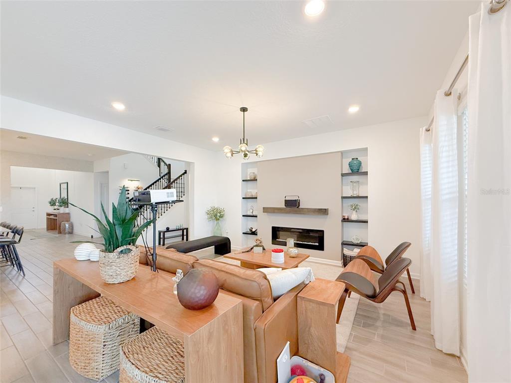 A living room features a fireplace, built-in shelving, a leather sofa, and a console table — 13993 TITLE WAY, WINTER GARDEN, FL