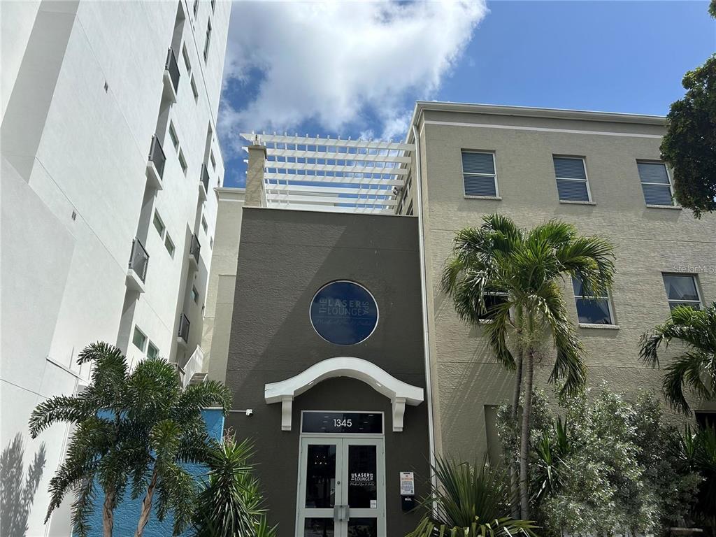 The exterior of a commercial building features a dark gray facade, a white pergola, and palm trees — 1345 2ND STREET UNIT C, SARASOTA, FL