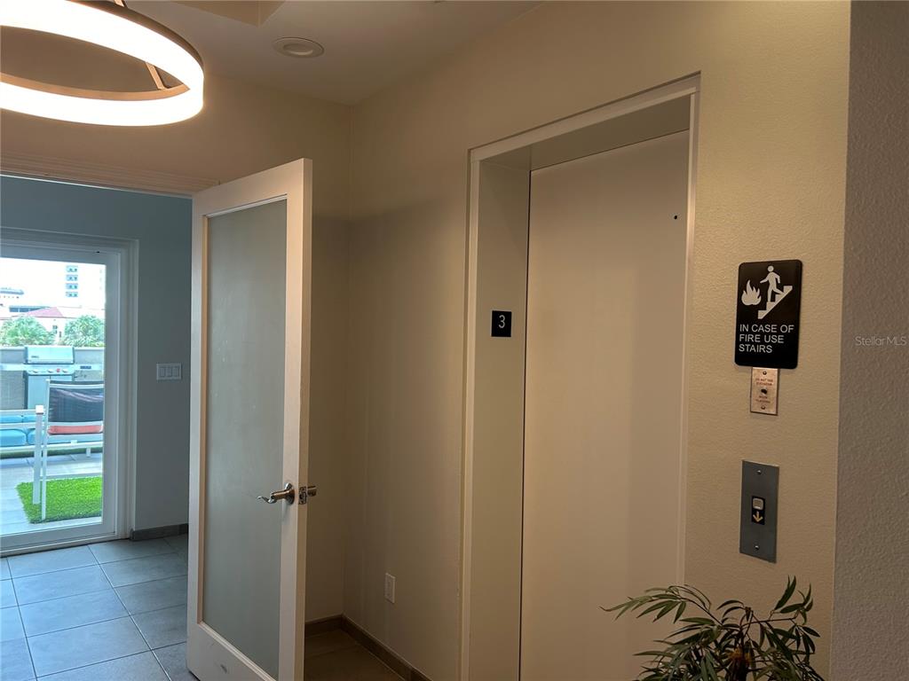 An elevator door with a fire safety sign is located next to a glass-paneled door — 1345 2ND STREET UNIT C, SARASOTA, FL