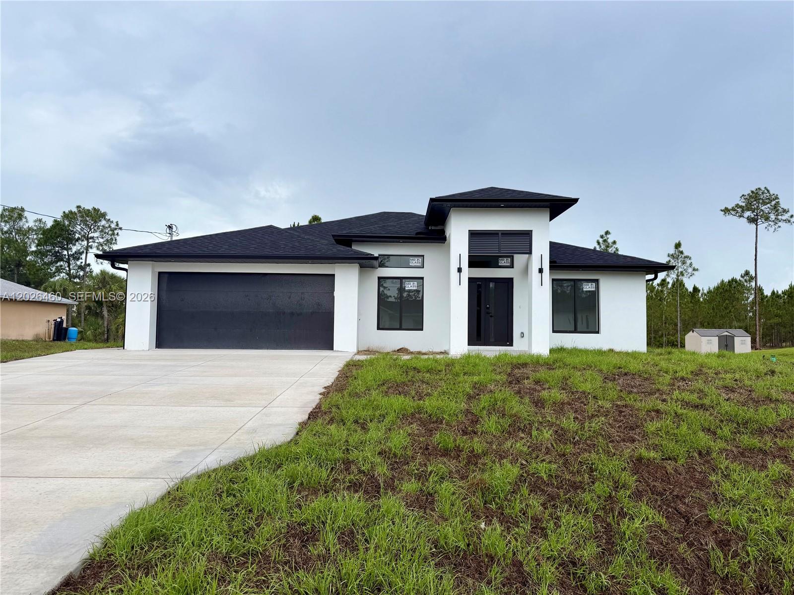 A modern, single-story white house with a black roof and a two-car garage — 911 Cleveland Ave, Lehigh Acres FL 33972, LEHIGH ACRES, FL