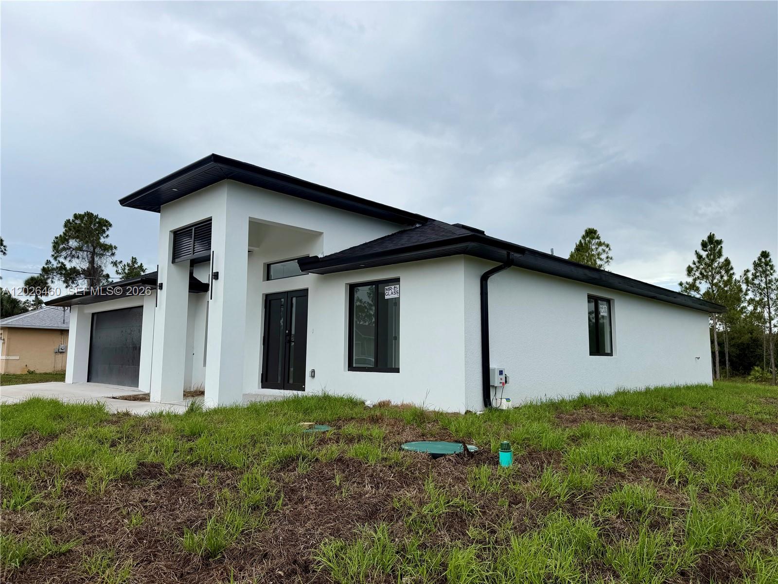 A modern, white single-story house with a black roof, garage, and dark-framed windows — 911 Cleveland Ave, Lehigh Acres FL 33972, LEHIGH ACRES, FL