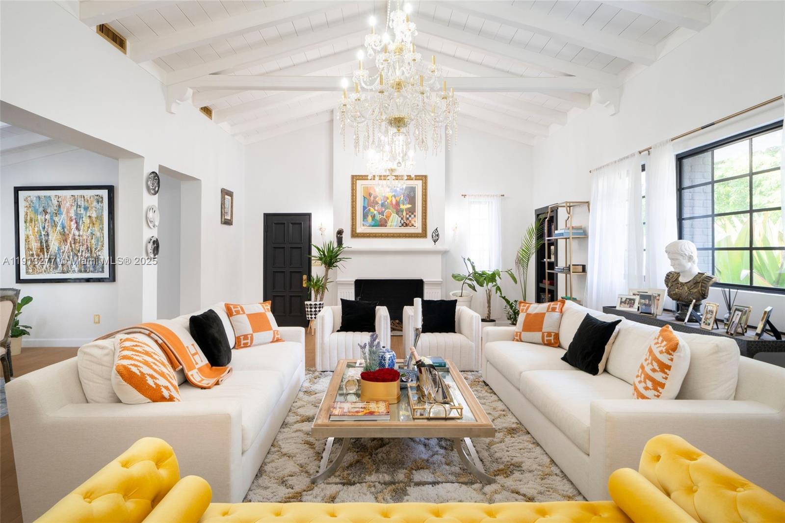 A bright living room features white sofas, a crystal chandelier, and a fireplace — 5149 Alton Rd, Miami Beach FL 33140, MIAMI BEACH, FL