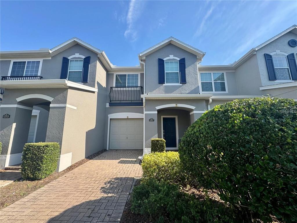 A two-story townhouse exterior features a paved driveway, a single-car garage, and blue shutters — 12117 CITRUSWOOD DRIVE, ORLANDO, FL