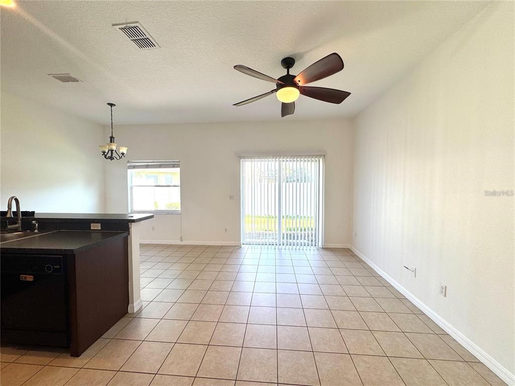 A tiled dining area features a ceiling fan, sliding glass doors, and an adjacent kitchen counter — 12117 CITRUSWOOD DRIVE, ORLANDO, FL