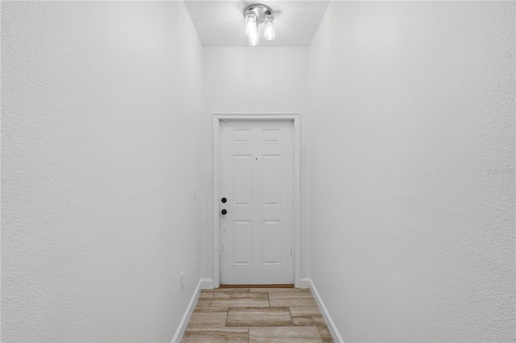 A narrow entryway features white walls, a white front door, and light-colored wood-look tile flooring — 1341 SHINNECOCK HILLS DRIVE, DAVENPORT, FL