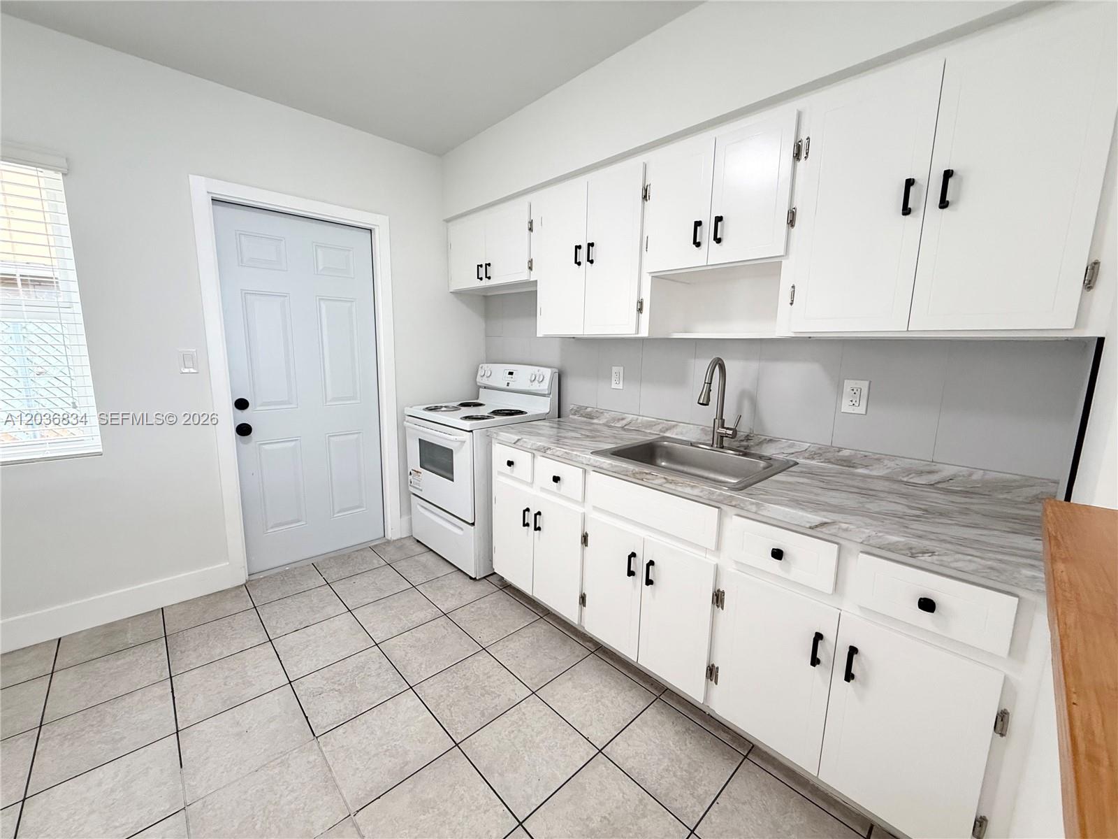 A kitchen features white cabinets, a white stove, a stainless steel sink, and tiled flooring — 2215 Madison St # 5, Hollywood FL 33020, HOLLYWOOD, FL