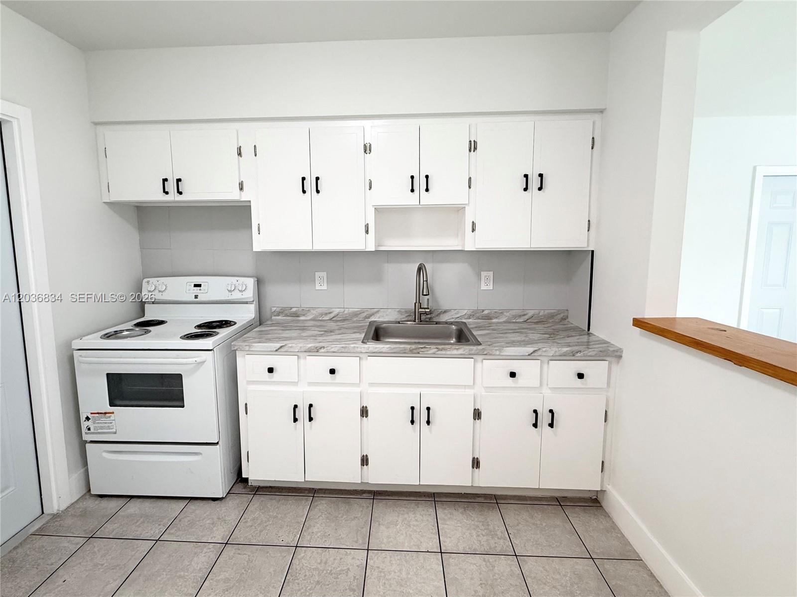 A kitchen features white cabinets, a stainless steel sink, a white stove, and tiled flooring — 2215 Madison St # 5, Hollywood FL 33020, HOLLYWOOD, FL