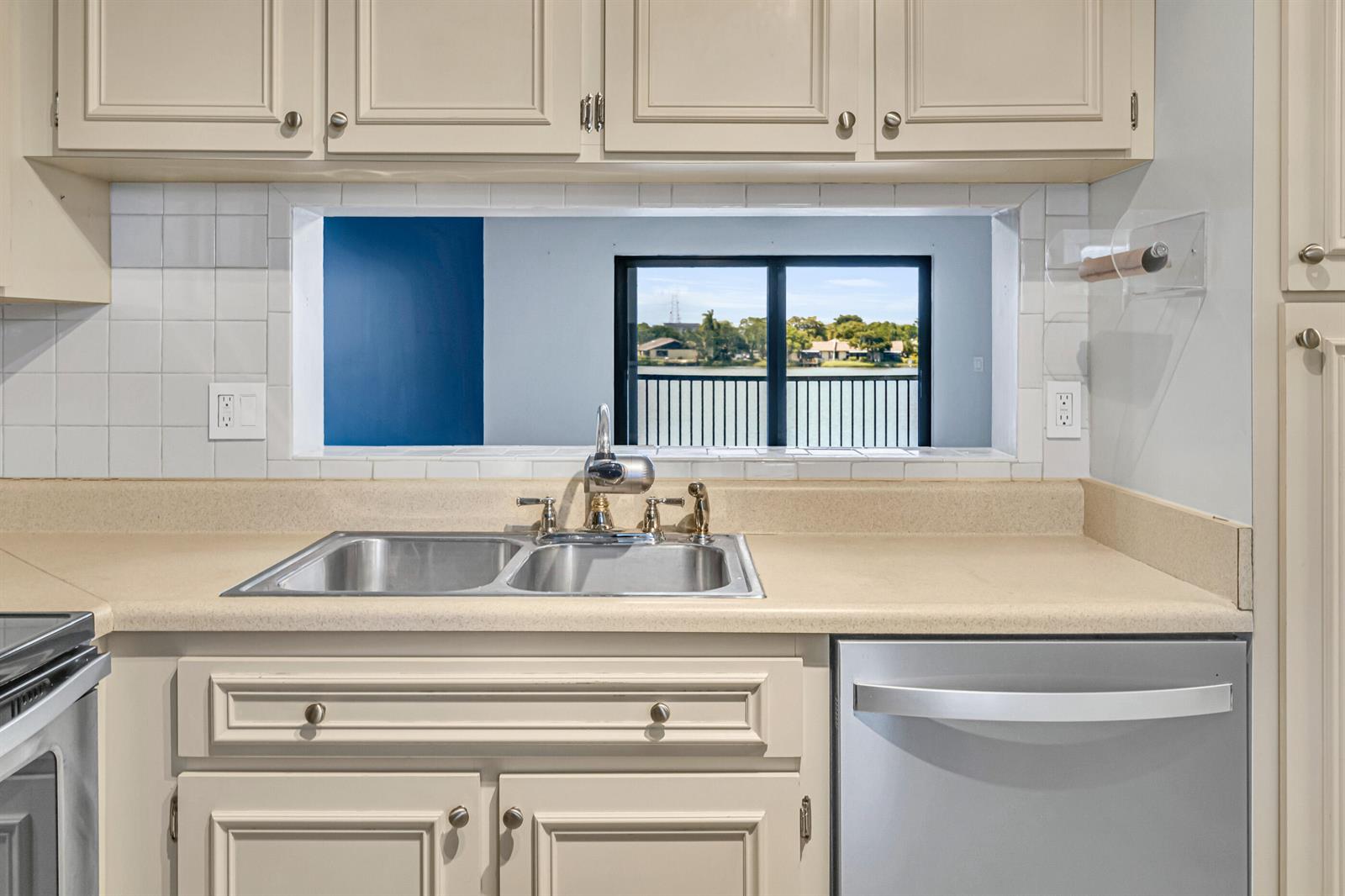 A kitchen sink with a pass-through window overlooking a lake and a balcony — 5510 Lakeside Drive # 202, Margate FL 33063, MARGATE, FL
