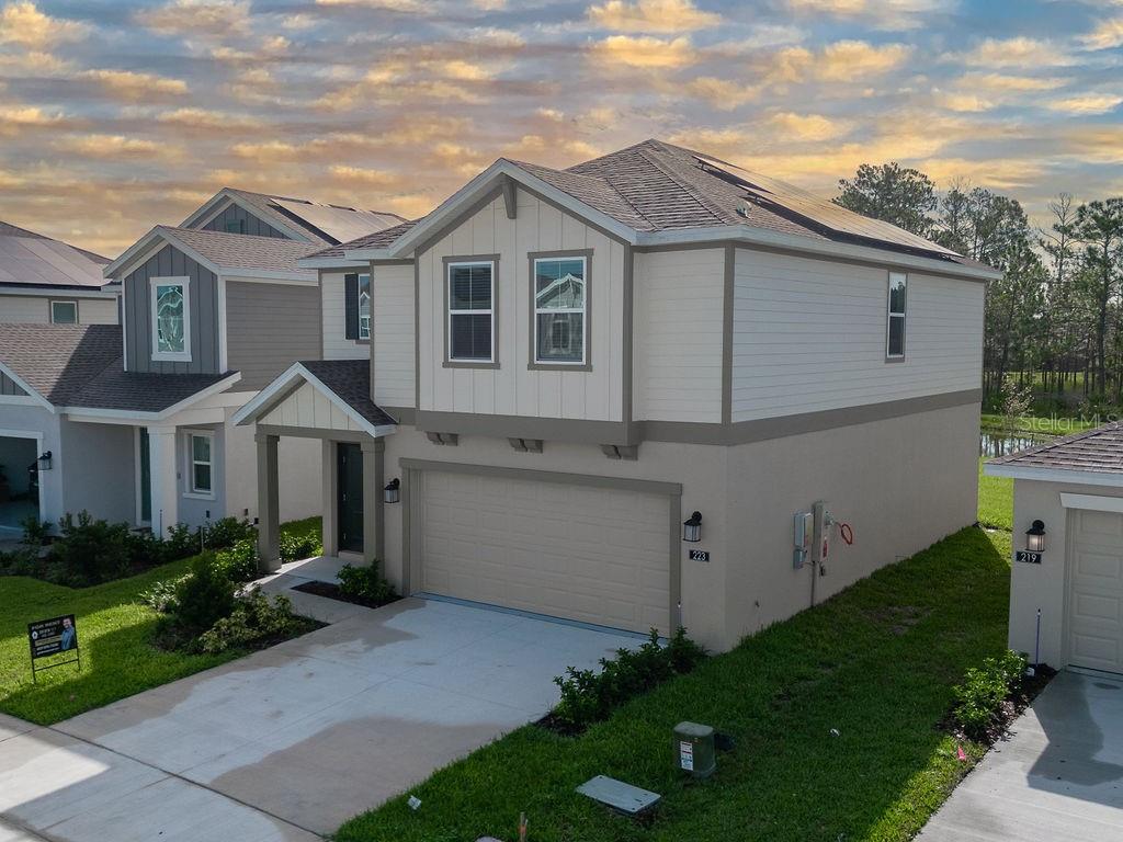An exterior view of a two-story suburban house with a beige stucco and siding facade — 223 BRAVE ROAD, DAVENPORT, FL