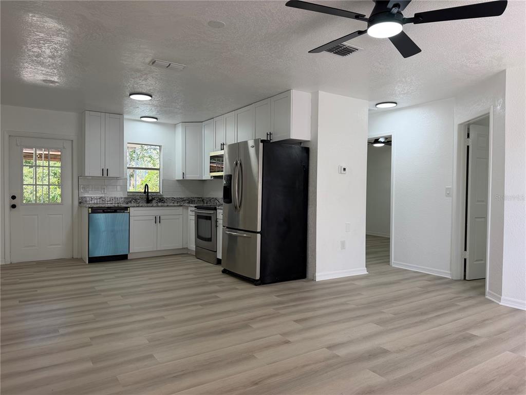 A kitchen with white cabinets, stainless steel appliances, and light wood-look flooring — 12022 CHUCK CIRCLE, HUDSON, FL