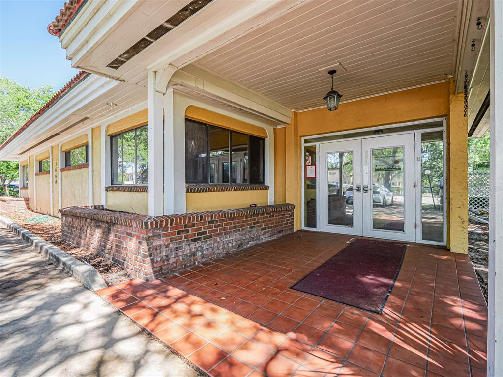 The exterior entrance of a building features a covered porch with brick walls and tile flooring — 3660 20TH STREET, VERO BEACH, FL