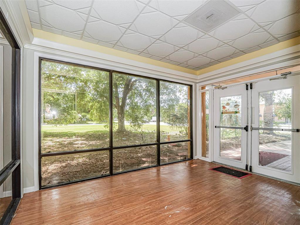 A sunroom with wood-look flooring, a patterned drop ceiling, large windows, and double glass doors — 3660 20TH STREET, VERO BEACH, FL