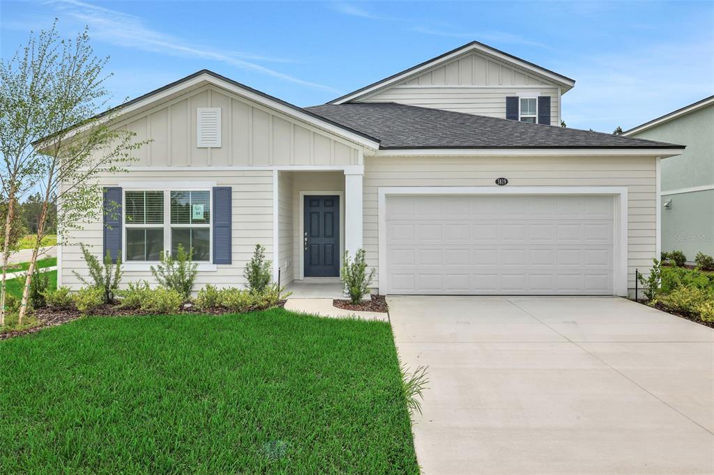 A single-story house with light siding, a two-car garage, and a dark blue front door — 3819 HOLSTEIN WAY, GREEN COVE SPRINGS, FL