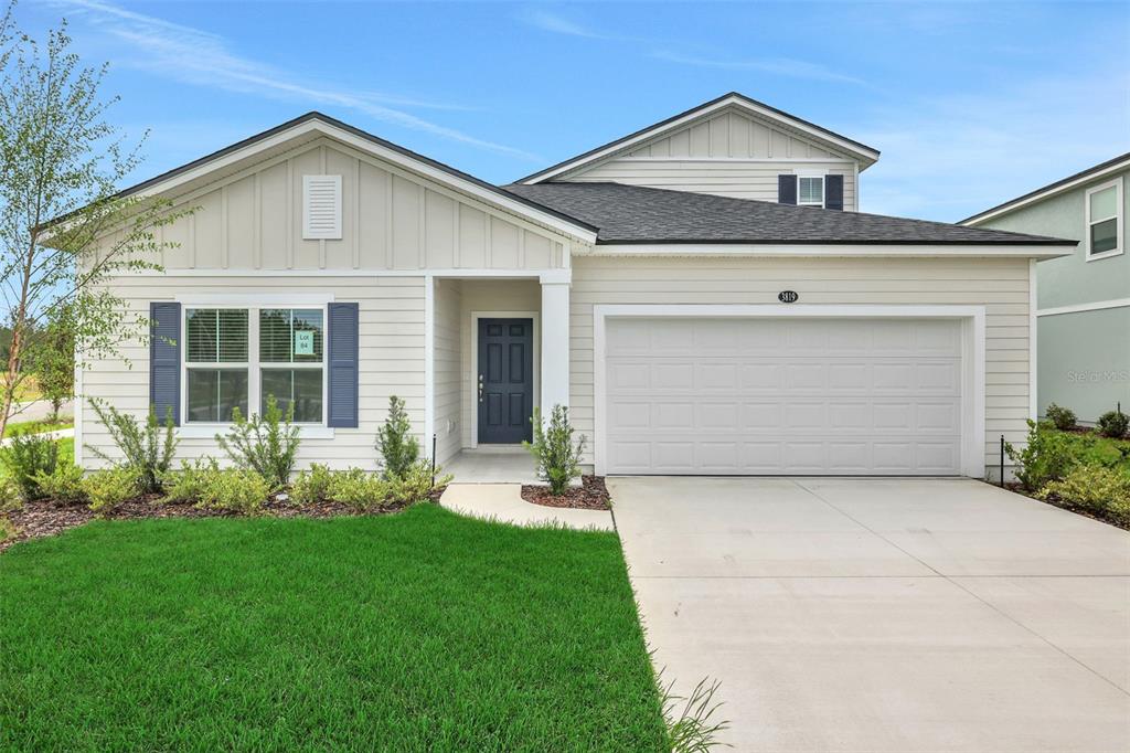 A single-story house with light siding, a dark blue front door, and a two-car garage — 3819 HOLSTEIN WAY, GREEN COVE SPRINGS, FL