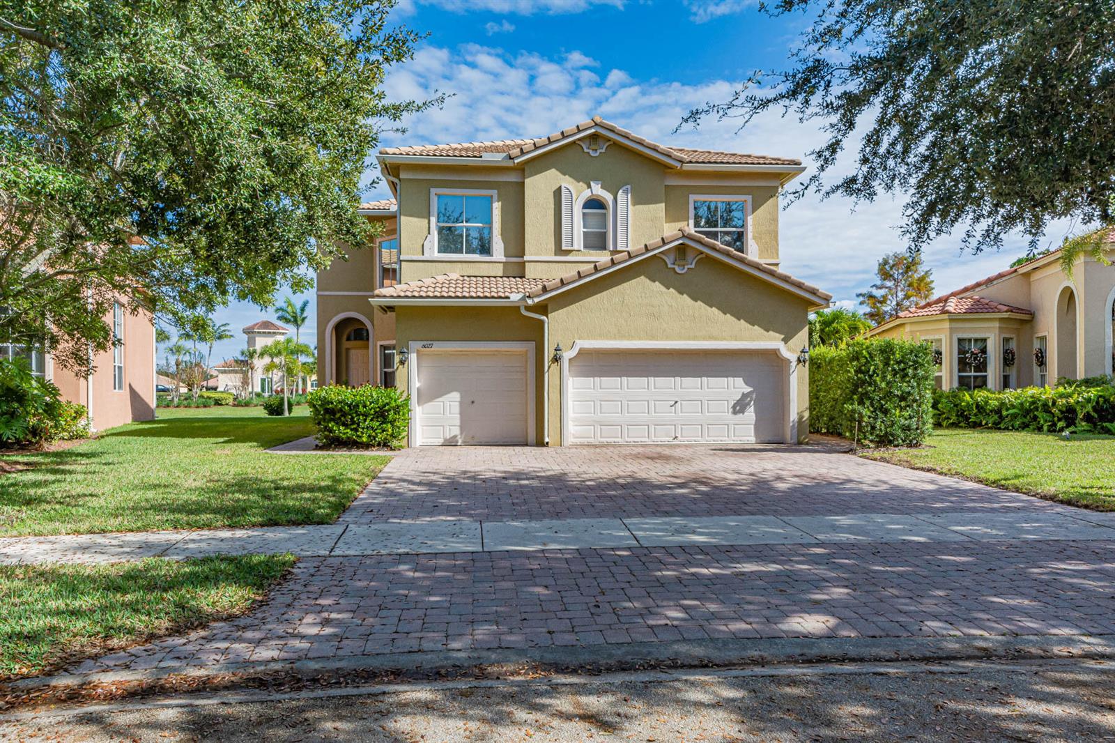 A two-story house with a tan stucco exterior, a tile roof, and a paved driveway — 6027 Arlington Way, Fort Pierce FL 34951, FORT PIERCE, FL