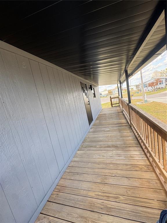 A long wooden porch with a gray paneled wall and a black door — 5035 SOUTHSHORE DRIVE, POLK CITY, FL
