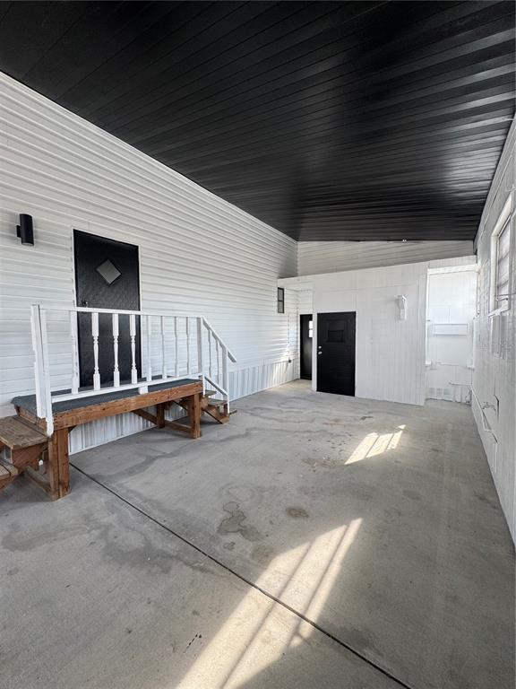 A covered concrete patio features white siding, a black ceiling, and a wooden staircase — 5035 SOUTHSHORE DRIVE, POLK CITY, FL